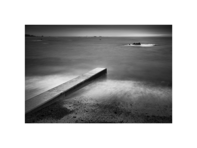Concrete, rocks, and distant lighthouse, L'Eree Bay, Guernsey. / Wasserlandschaften  Fotografie von Fotograf Tim Harvey ★1 | STRKNG