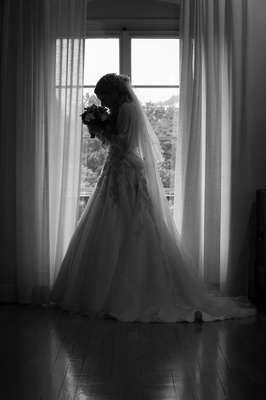 Braut mit dem Brautstrauss vor dem Fenster, Schwarz-Weiss / Wedding  photography by Photographer Wolf | STRKNG